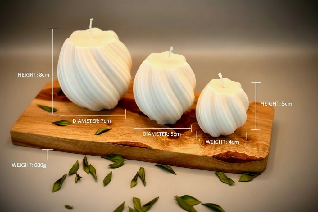 Three white spherical candles on a wooden board with green leaves scattered around.